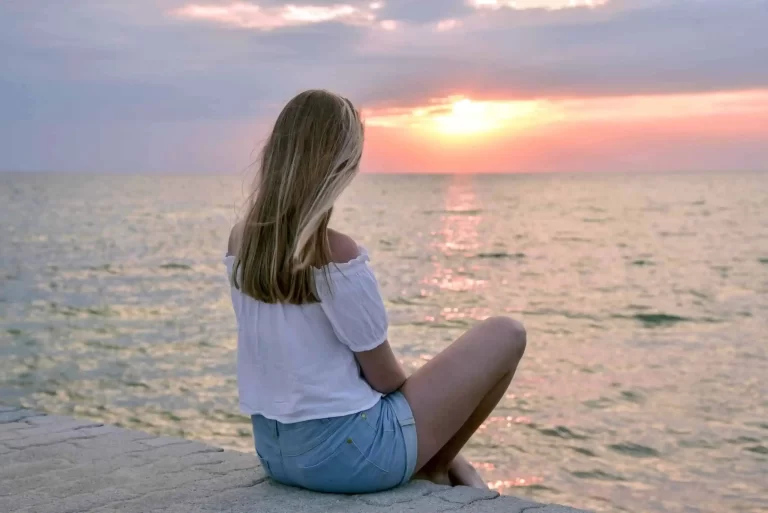 Girl looking at sunset, illustrating tips for practicing mindfulness and being present in the moment